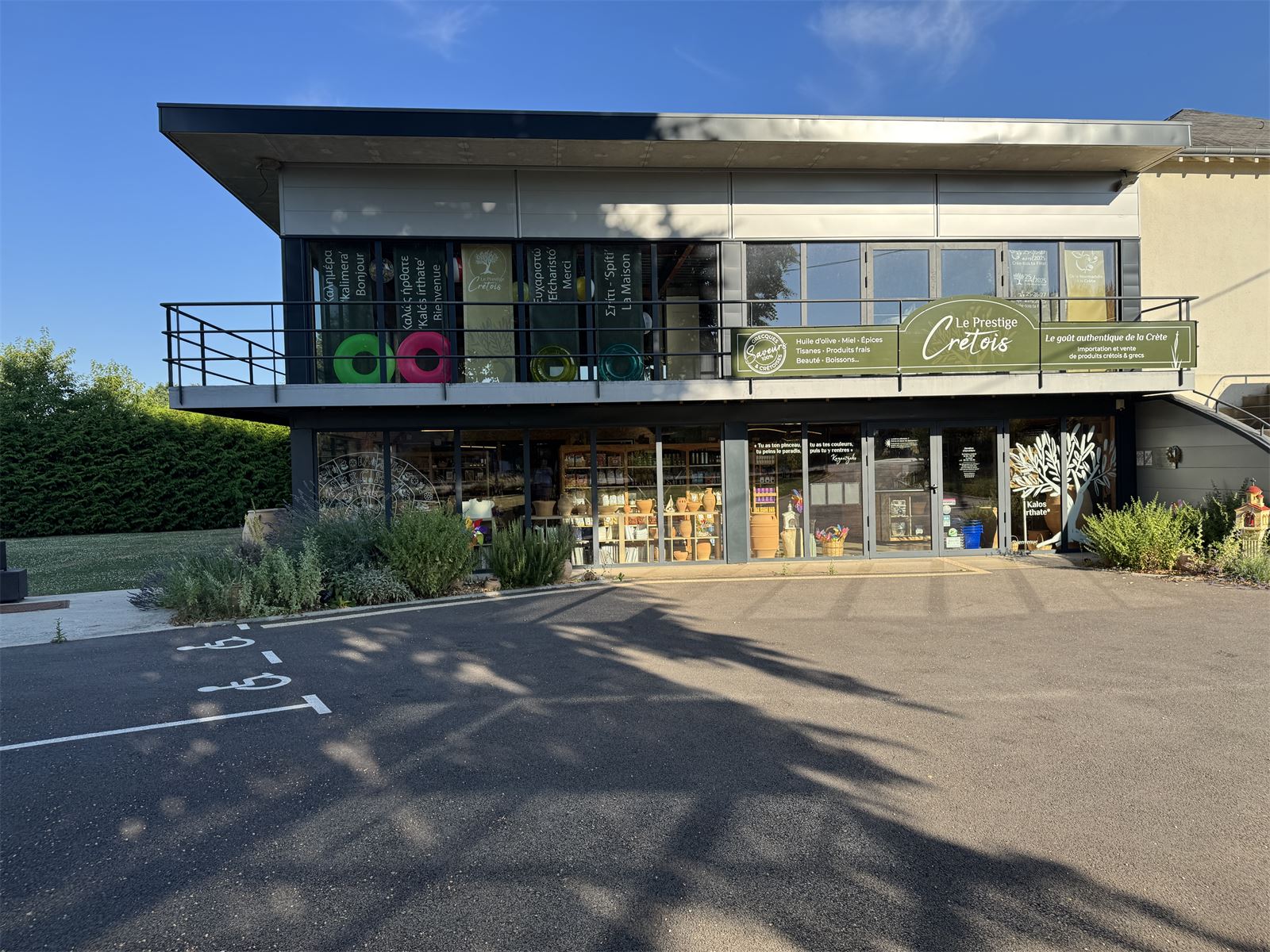 Fa&ccedil;ade de notre &eacute;picerie grecque &agrave; Messei, dans l'Orne - banni&egrave;re verte Le Prestige Cr&eacute;tois et vitrines d&eacute;cor&eacute;es